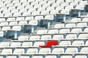 Sarkans krēsls starp baltiem krēsliem stadionā