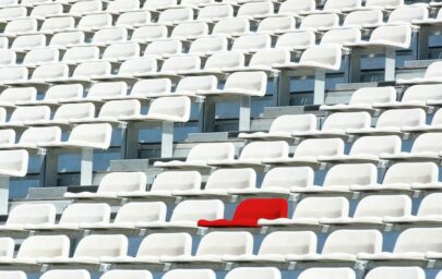 Sarkans krēsls starp baltiem krēsliem stadionā